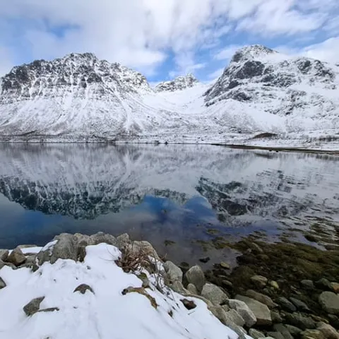 Snowy peaks mirrored in the still fjord