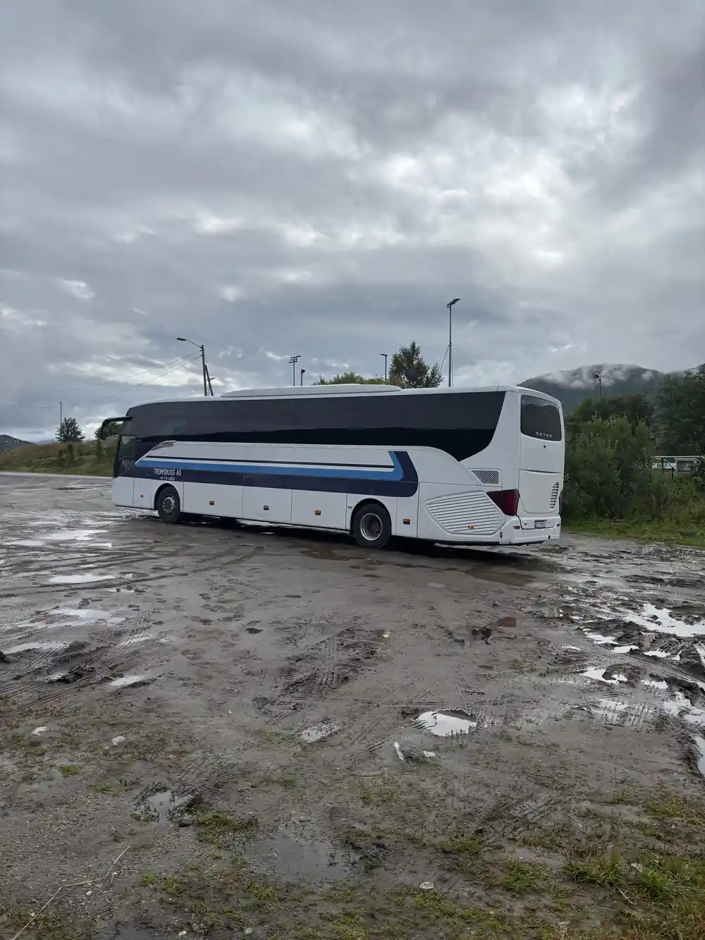 The expedition coach parked on gravel by the shore