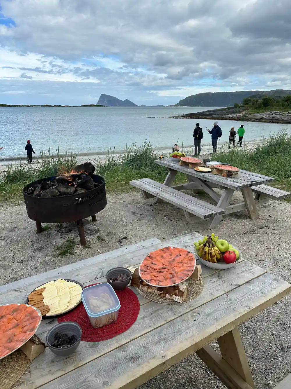 A fire pit and picnic tables set out on the sand