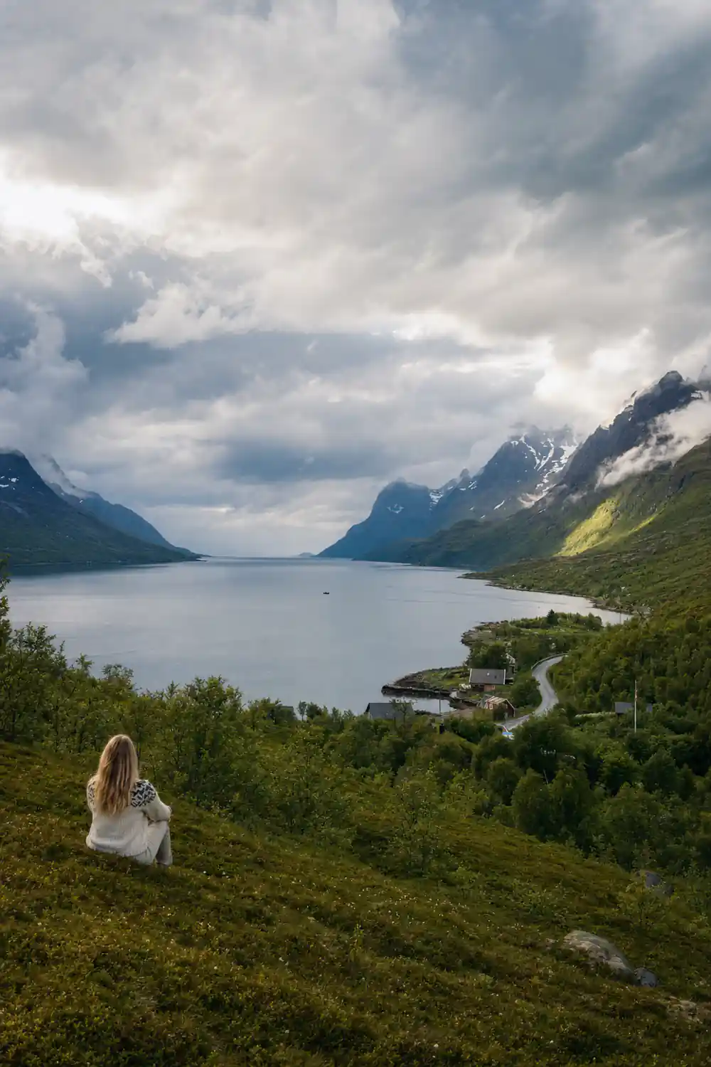 A grey fjord running between steep cloud-covered mountains