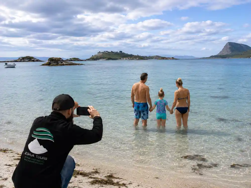 A guide photographing a family standing in the shallows