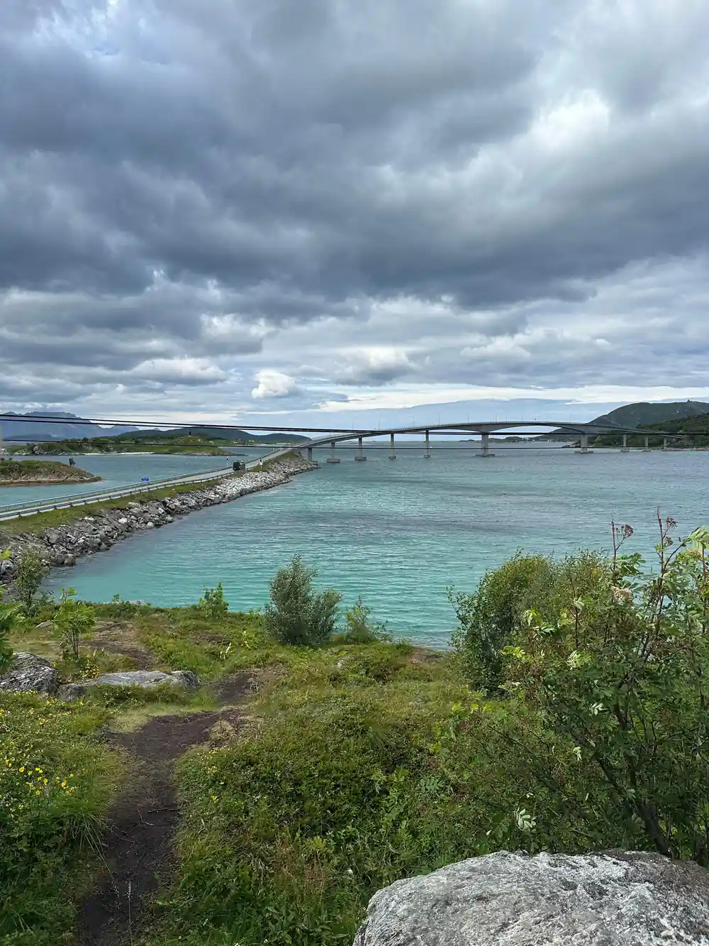 A long bridge over turquoise water seen from a hill