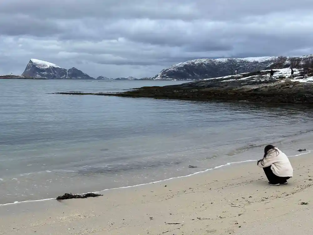 A person walking a broad pale beach in winter