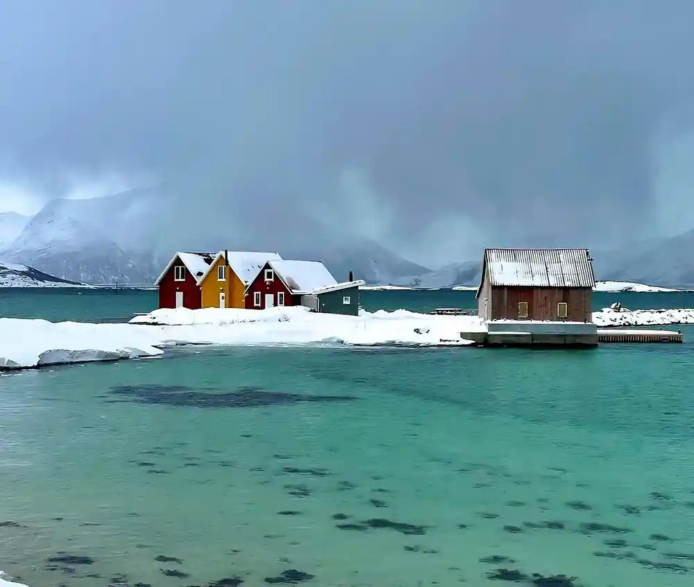 Red cabins on stilts above clear green water in winter