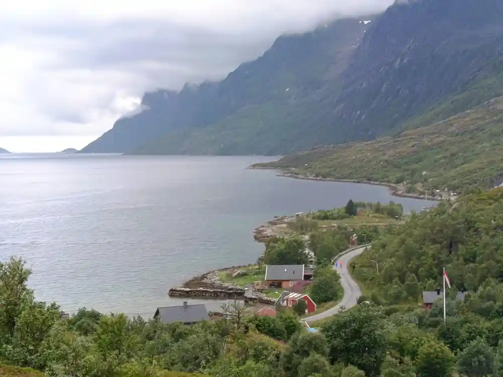 A road running along the shore beneath a steep mountain