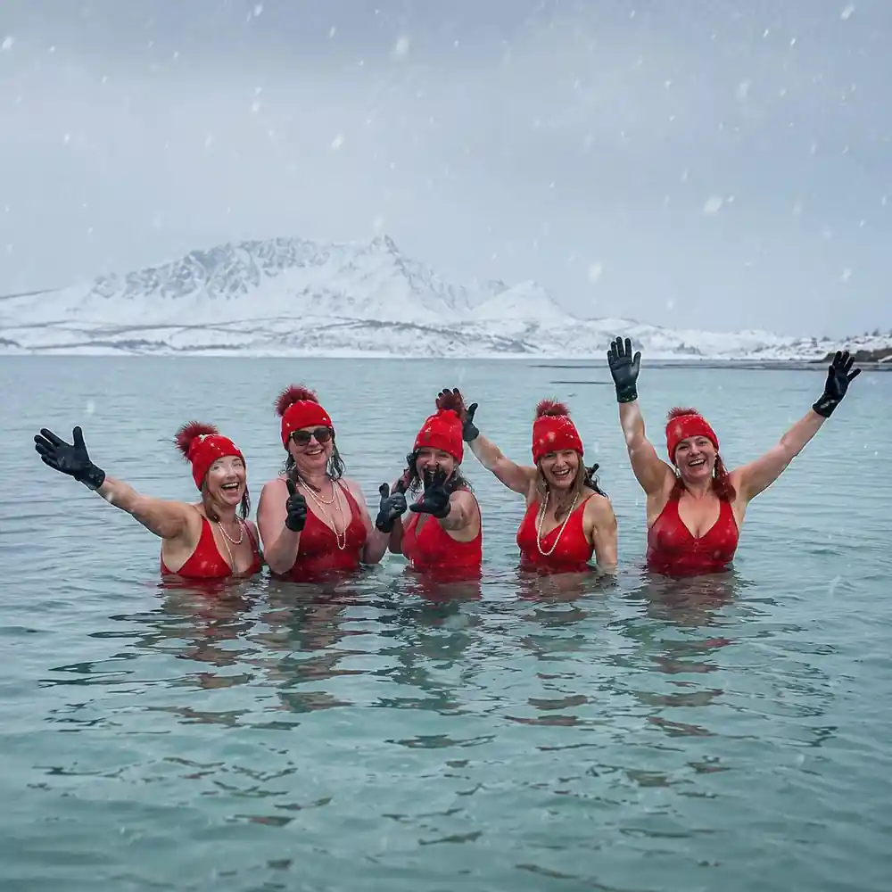 Swimmers in red caps standing in the sea in falling snow