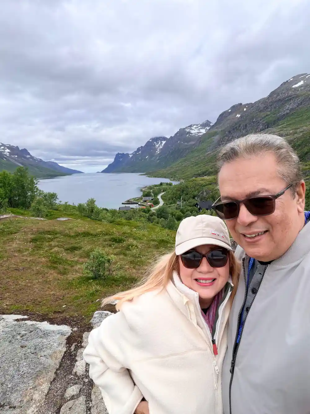 Two guests taking a photograph with green mountains behind