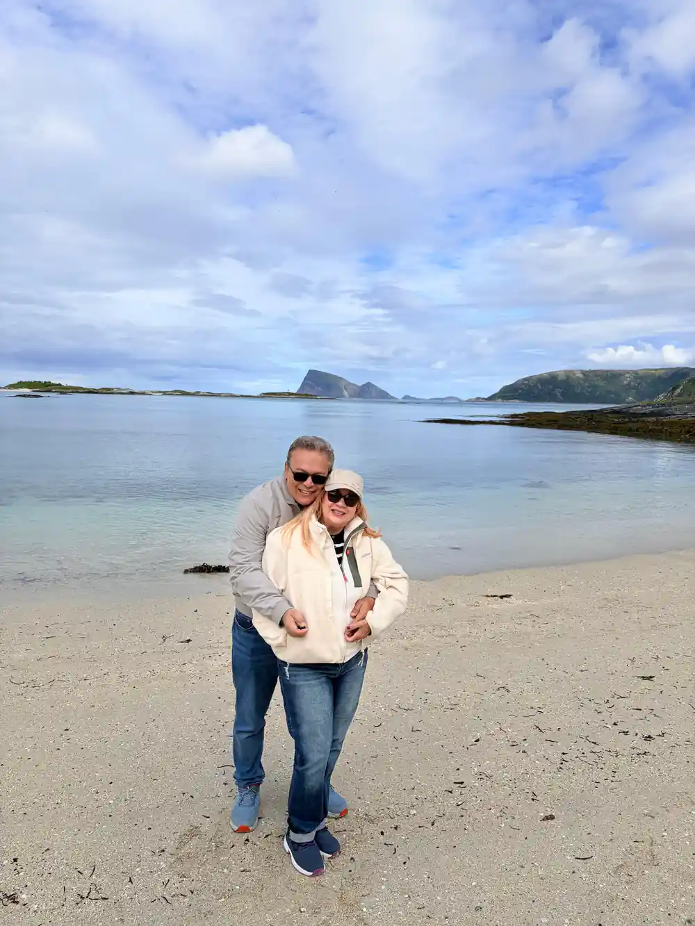 Two guests on a wide pale beach with islands beyond